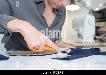 Découper des morceaux de tissu à partir d'un patron de couture. Banque D'Images