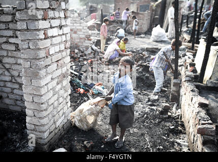 Beijing, l'Inde. 19 Oct, 2015. Un enfant porte objets trouvés dans les restes après un incendie en Mangolpuri area, New Delhi, Inde, le 19 octobre 2015. Un incendie majeur détruit plus de 300 maisons dans un bidonville de la capitale indienne Lundi, un haut responsable de la police a dit. © Bi Xiaoyang/Xinhua/Alamy Live News Banque D'Images