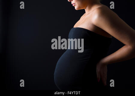 Jeune femme enceinte avec les mains sur son dos Banque D'Images