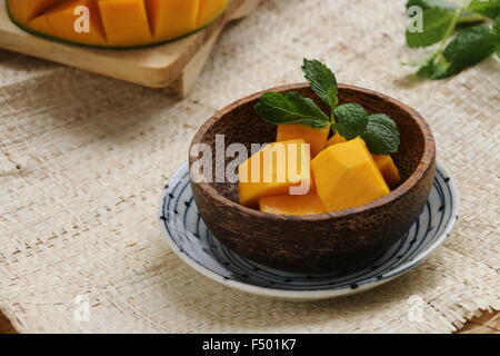 Aromatique doux coupé en cubes de mangue et servi sur un petit bol de noix de coco, et doublé d'une plaque en céramique. Banque D'Images