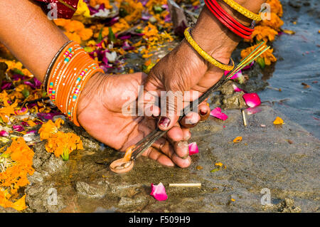 Mains de 2 femmes à l'encense herbal éclairage Le sangam, le confluent des fleuves Ganges, yamuna et saraswati, à kumbha mela Banque D'Images