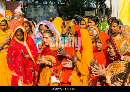 Groupe de femmes habillées de couleurs priant au sangam, le confluent des fleuves Ganges, yamuna et saraswati, à kumbha mela Banque D'Images