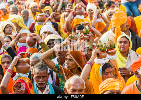 Procession de fidèles vêtus d'orange, certaines portant des offrandes sur leur tête, au sangam, le confluent des fleuves Ganges Banque D'Images