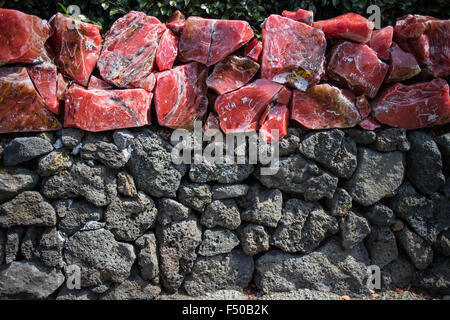 Un mur en pierre volcanique traditionnel sur l'île de Jeju en Corée avec des roches rouges sur le dessus Banque D'Images