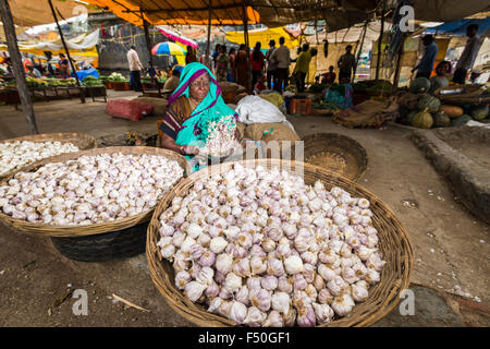 Une femme est la vente de l'ail dans des paniers à l'hebdomadaire de légumes du marché Banque D'Images