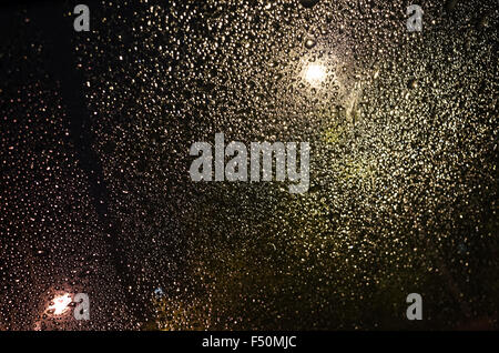 Verre humide avec des gouttelettes de pluie, sombre arrière-plan photo floue avec selective focus Banque D'Images