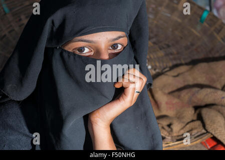 Une jeune femme musulmane, son visage couvert par un voile noir, hijab, vend des légumes sur le marché Banque D'Images