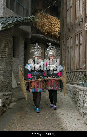 Paire de support vert jupe des femmes Miao marchant dans un village-rue, Shiqiao Village Miao, province de Guizhou, Chine Banque D'Images