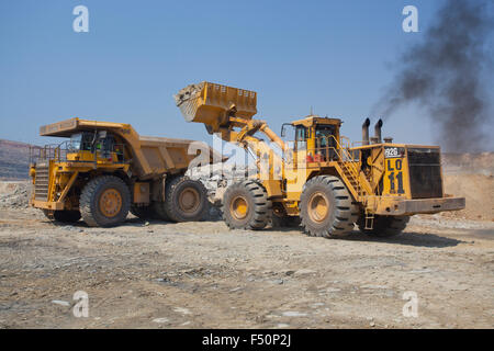 Photo d'action d'un chargeur avant de remplir une grande distance de la mine dump truck avec la terre excavée. L'exploitation minière en Zambie, l'Afrique. Banque D'Images