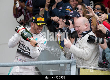 Austin, TX USA Octobre 25, 2015 : pilote de Formule 1 Lewis Hamilton célèbre sa victoire par pulvérisation champagne plus de spectateurs après le Grand Prix des Etats-Unis qui a décroché son titre de champion du monde. Banque D'Images