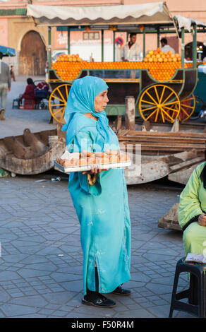 Femme musulmane locale en bleu jilbab holding a tray de gâteaux, place Jamaa el Fna, Médina, Marrakech, Maroc, Afrique du Nord Banque D'Images