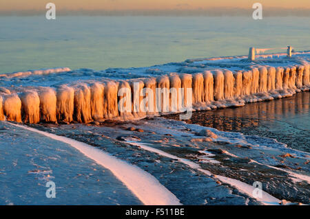 La glace se forme sur un brise-lames dans le port de Chicago's 31st Street, tout en reflétant la lumière du soleil tôt lorsqu'il s'ouvre sur la scène. Chicago, Illinois, États-Unis Banque D'Images