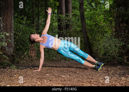 Athletic woman une planche sur un sentier forestier Banque D'Images