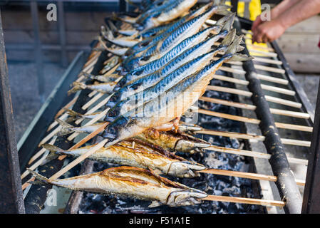 Stockfisch, un plat de poisson préparé sur un bâton en bois, est grillé sur un barbecue Banque D'Images