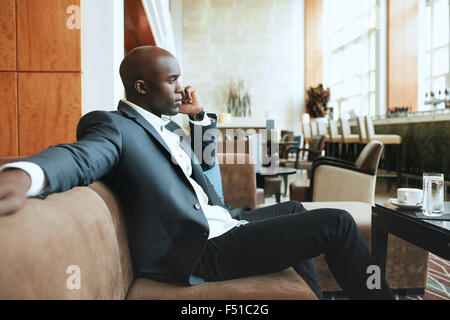 Young businessman sitting on sofa détendue au hall de l'hôtel Faire un appel téléphonique, l'attente de quelqu'un. Banque D'Images