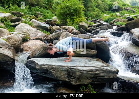 Les jeunes fit woman doing yoga oudoors at waterfall Banque D'Images