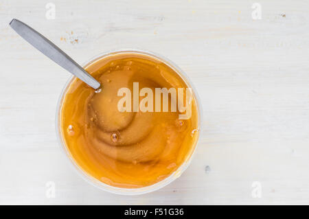 Pot en plastique noir dense avec une cuillère de miel vue supérieure Banque D'Images