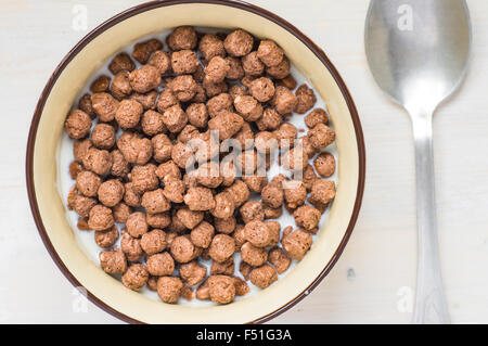 Boules au chocolat pour le petit déjeuner dans un bol près de la cuillère vue supérieure Banque D'Images