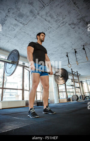 Full Length portrait of a male bodybuilder entraînement avec haltères longs en fitness Banque D'Images