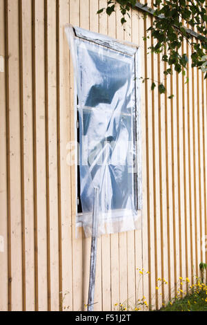 Une fenêtre en plastique, sur une vieille maison jaune Banque D'Images