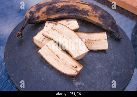 Vieux morceaux de banane plantain, sur une plaque en pierre Banque D'Images