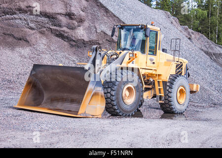 Un bulldozer solitaire, debout devant un grand tas de sable Banque D'Images