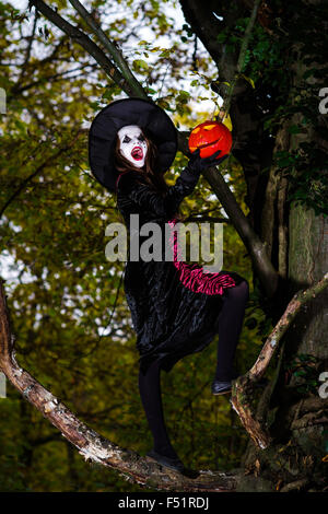 Teenage girl habillé en costume assis sur l'arbre, Halloween concept Banque D'Images