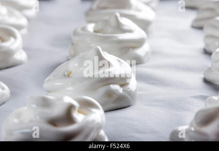 Meringues blanc sur du papier sulfurisé sur une plaque à pâtisserie Banque D'Images