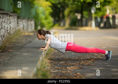 Jeune femme sportive faisant push-ups à l'extérieur. Banque D'Images