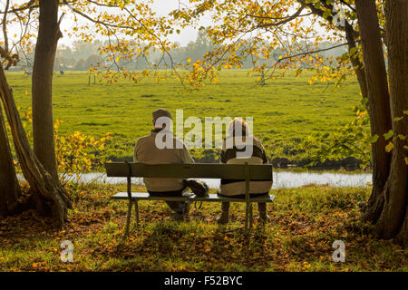 Un couple de profiter de la vue sur un banc dans le parc, au château de Duivenvoorde, Voorschoten, Hollande méridionale, Pays-Bas. Banque D'Images