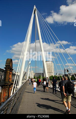 Les piétons circulant sur le Hungerford Bridge sur la Tamise à côté du London Eye à Londres, Angleterre, RU Banque D'Images