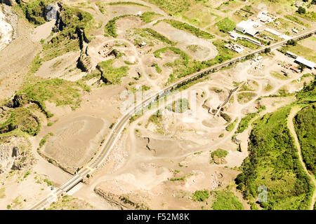 Une photographie aérienne montre une grande exploitation de carrière nichée dans un paysage vallonné et semi-aride. Une route pavée traverse le site, traversant un petit pont et passant près de pieux de terre excavés Banque D'Images