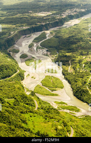 Une perspective aérienne capture une rivière sinueuse traversant une vallée verdoyante, avec de multiples canaux tressés et des barres de gravier exposées. La rivière est flanquée de collines escarpées et boisées Banque D'Images