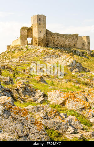L'image montre les ruines d'un ancien château de pierre perché au sommet d'une colline rocheuse accidentée. La structure comprend une tour carrée proéminente avec des ouvertures verticales étroites et une grande passerelle arquée, les deux Banque D'Images