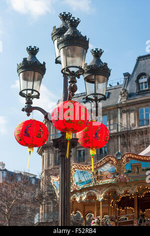 Lanternes chinoises pendaison le lampadaire avec un carrousel en arrière-plan pour l'festivités du Nouvel an chinois à Paris, France. Banque D'Images