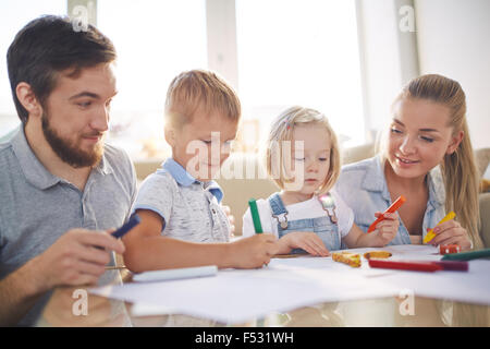 Les enfants et leurs parents avec des crayons dimensions ensemble à la maison Banque D'Images