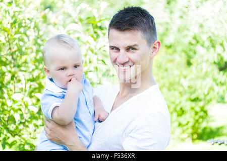 Charmant caucasian baby boy avec le père dans le jardin high key Banque D'Images