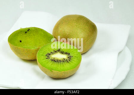 Trois kiwis, coupées en deux et ensemble, plein et vide, on white plate, Close up, macro, horizontal, fond blanc Banque D'Images