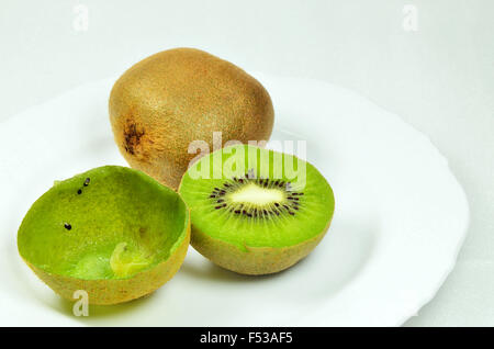 Trois kiwis, coupées en deux et ensemble, plein et vide, on white plate, Close up, macro, horizontal, fond blanc Banque D'Images