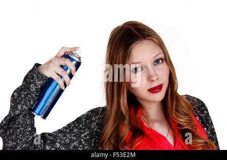 Une jeune femme se coiffer et mettre sur hairspray, isolée pour fond blanc. Banque D'Images