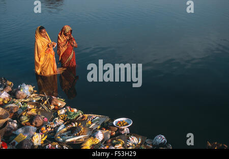 Deux femmes hindoues célèbrent le festival des 'Chhath puja en adorant le dieu soleil dans un étang. Banque D'Images