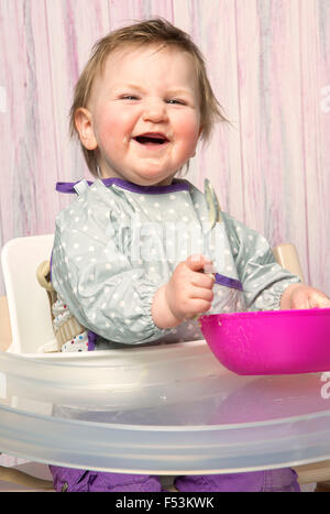 Bébé, 6 à 12 mois, écraser, de l'alimentation, une cuillère, des aliments solides, chaise haute, studio, portrait, Banque D'Images