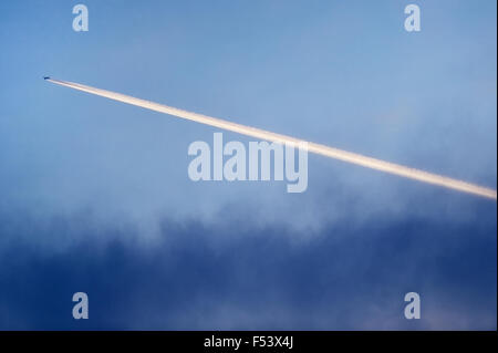 Les traînées de condensation d'avion sont vus sur le ciel au coucher du soleil Banque D'Images