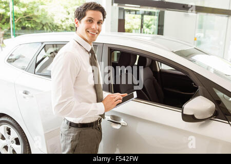 Smiling salesman en utilisant une voiture près de tablette Banque D'Images