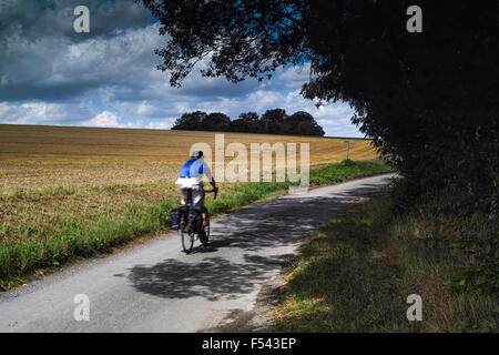 An English country Lane dans le Hertfordshire en face d'un champ de blé et de maturation avec un cycliste de loisirs en passant par Banque D'Images