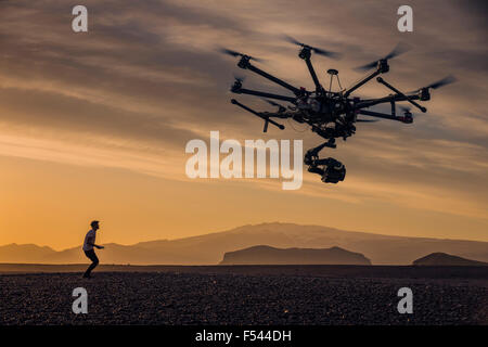 L'homme aux commandes d'un drone contrôlé à distance avec un appareil photo au coucher du soleil sur les hauts plateaux du centre, de l'Islande Banque D'Images