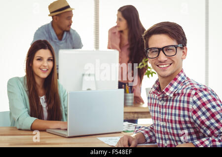 Les jeunes travailleurs créatifs smiling at camera Banque D'Images