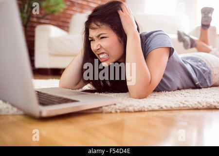Asian angry woman using laptop on floor Banque D'Images
