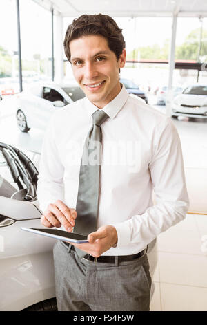 Smiling salesman en utilisant une voiture près de tablette Banque D'Images