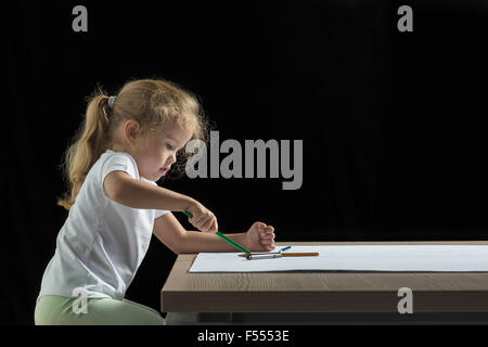 Vue latérale du dessin de fille sur le papier au tableau sur fond noir Banque D'Images